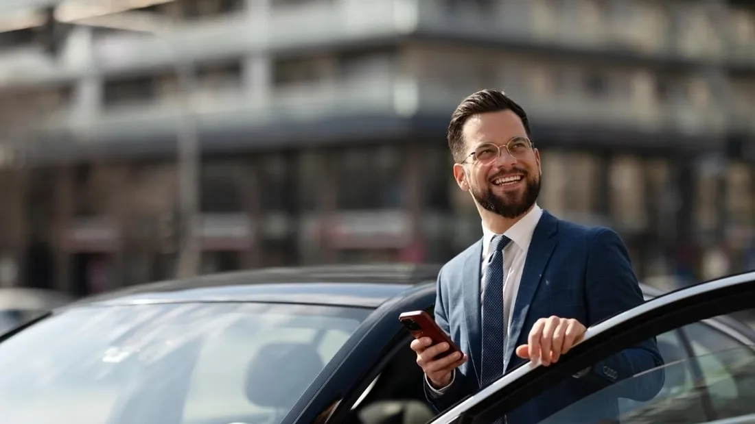 Business traveller standing beside an executive car